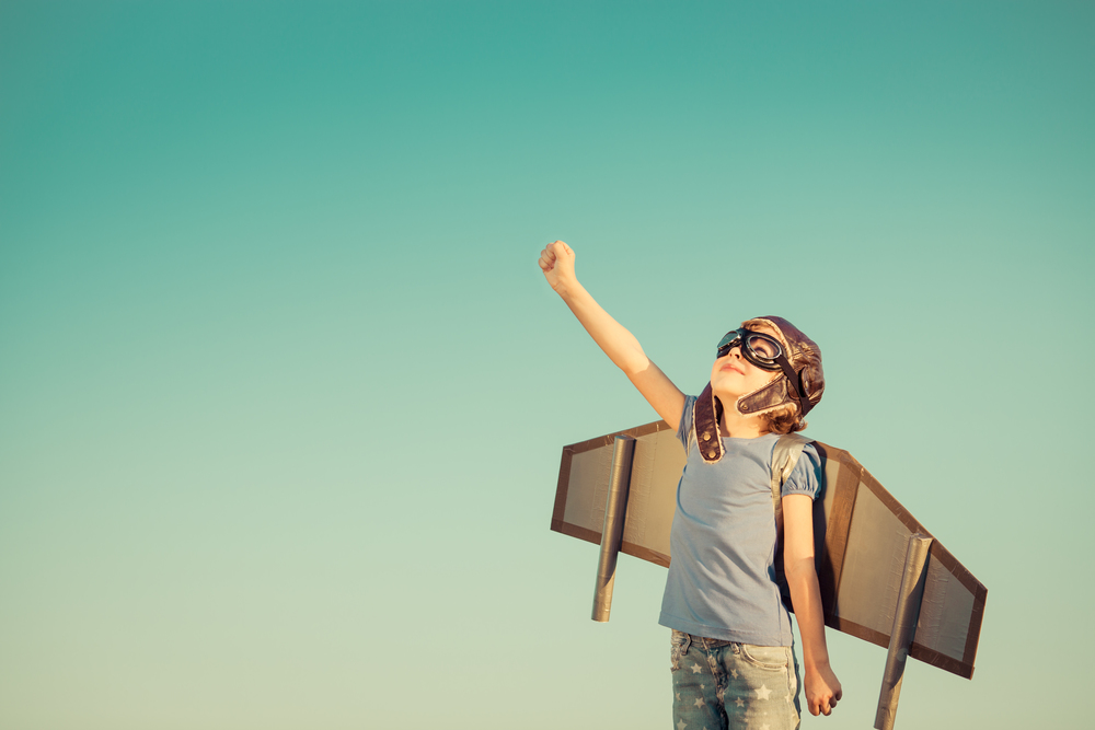 Little boy with aviator helmet and airplane wings with his fist in the air